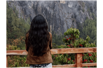 Blooming rhododendron tree with red flowers in Darjeeling, framed by Himalayan forest and colorful prayer flags