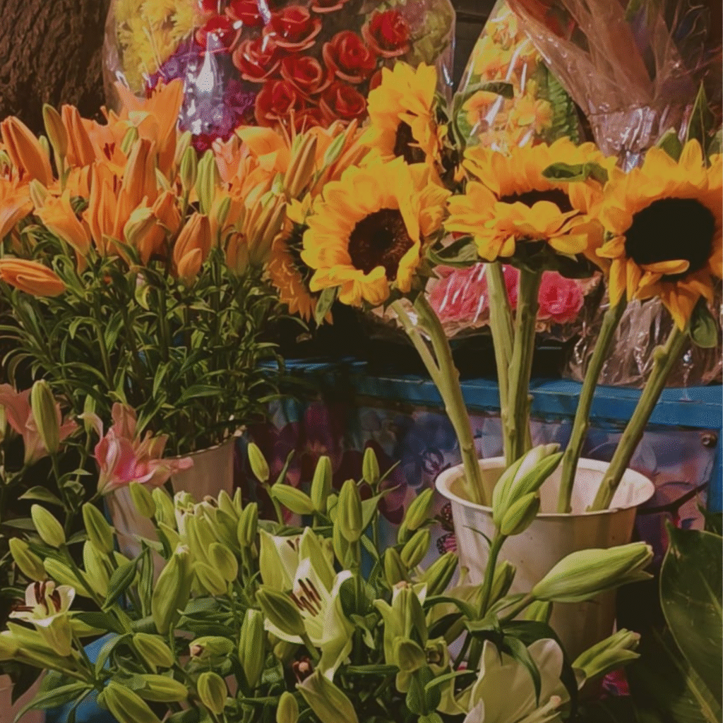 A display of vibrant sunflowers and lilies at a flower shop.